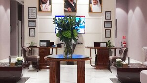 A reception area with a marble floor, wooden reception desk, and framed portraits on the wall.