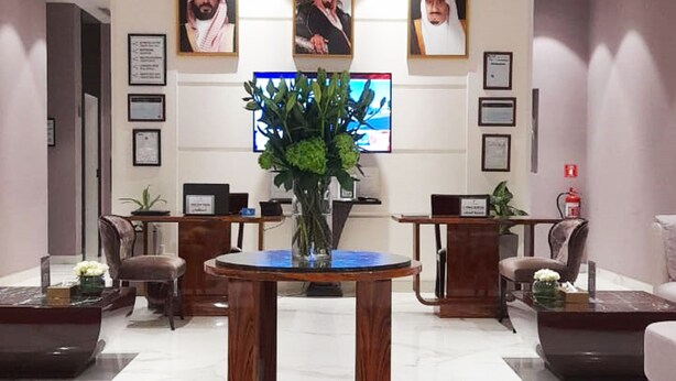 A reception area with a marble floor, wooden reception desk, and framed portraits on the wall. - Vivienda Hotel Villas Al Hada (Riyadh)