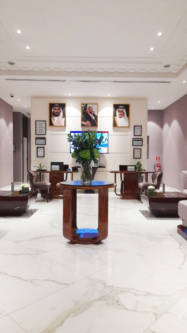A reception area with a marble floor, wooden reception desk, and framed portraits on the wall. - Vivienda Hotel Villas Al Hada (Riyadh)