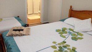 A hotel room with a wooden bed, a bathroom door, and a towel on the bed. - Comfortable Family room with Tv, Free Fast Wifi, Sleeps 3 (Hayes)