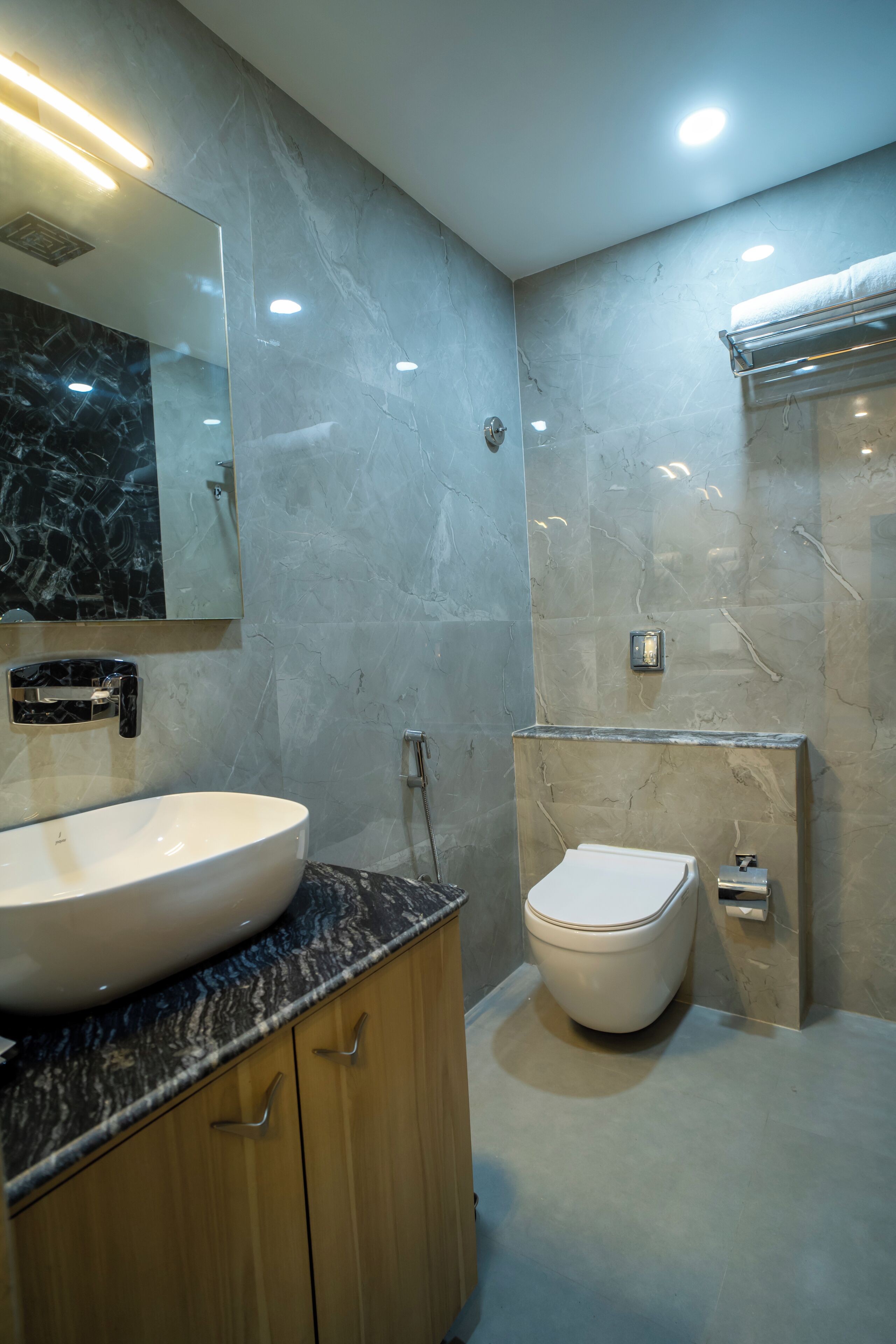 A modern bathroom with a marble sink, a toilet, and a mirror.