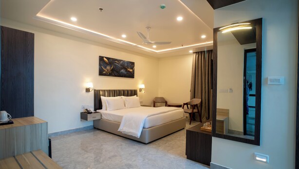 A modern hotel room with a large bed, bedside tables, a desk, and a mirror.