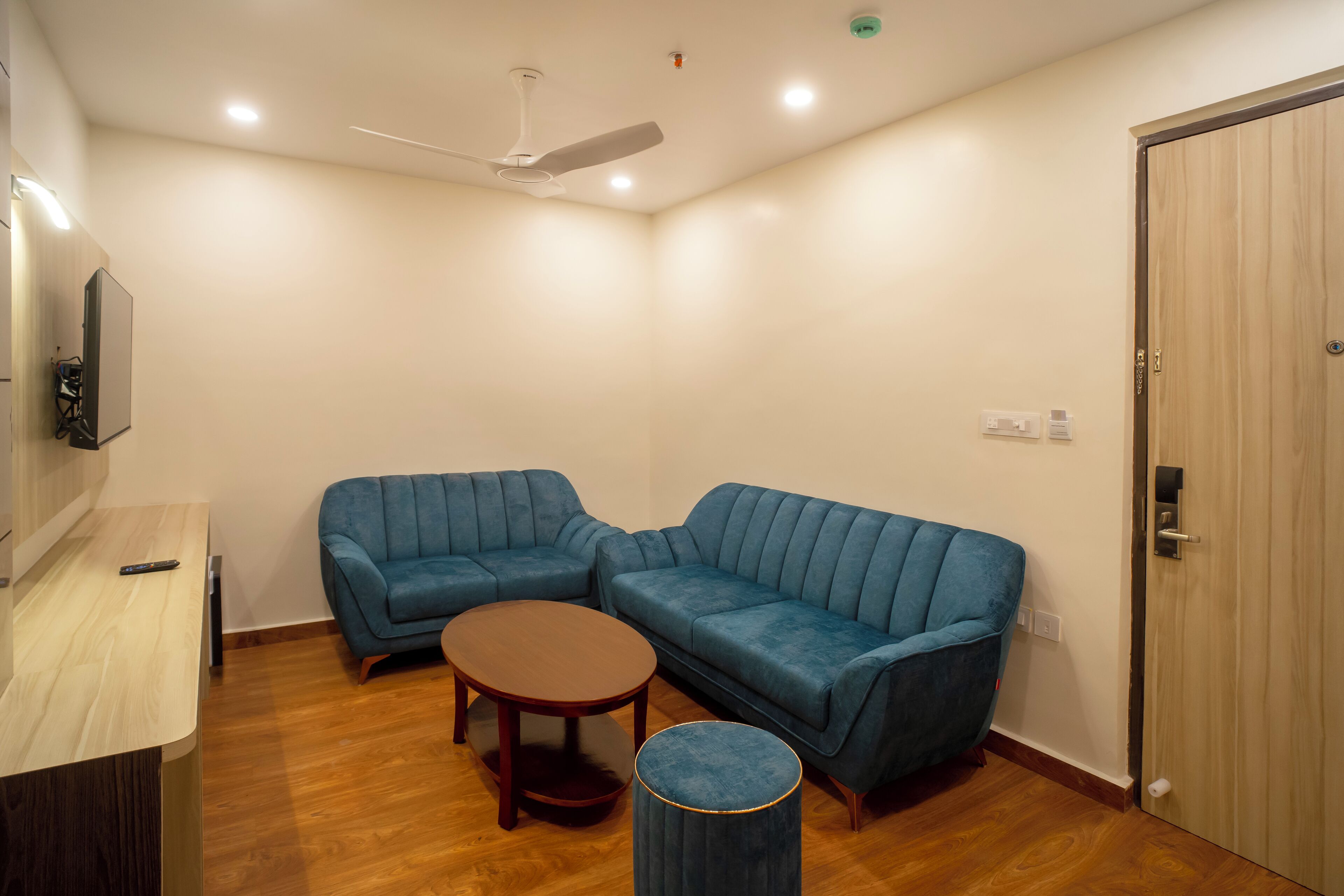 A room with two blue sofas, a wooden coffee table, and a small round ottoman.
