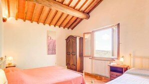 Un dormitorio con dos camas, techo de madera, ventana y radiador.