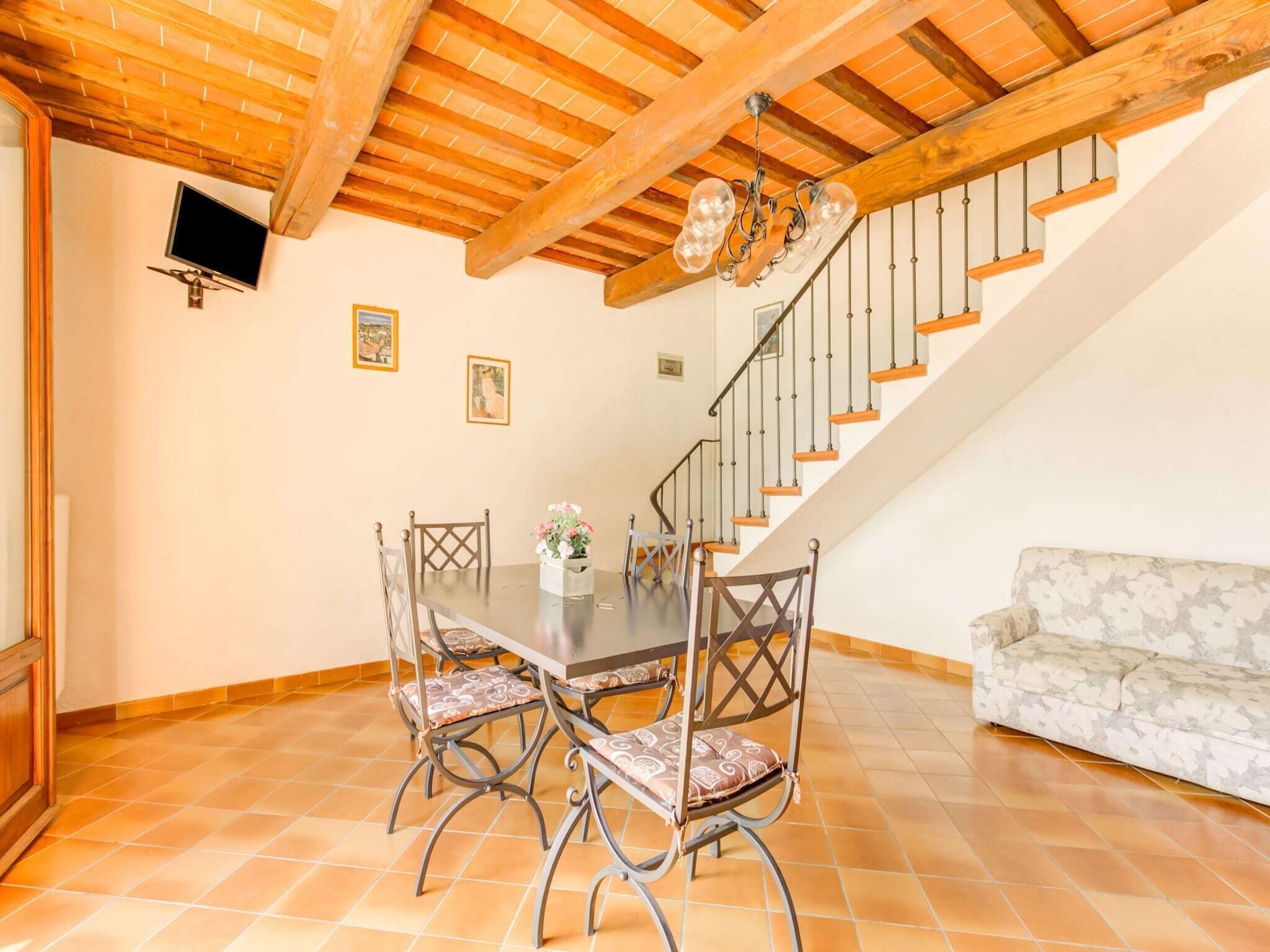 Un área de comedor con techo de madera, una escalera y un sofá.