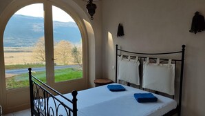 Een slaapkamer met een bed, een raam en uitzicht op het landschap.
