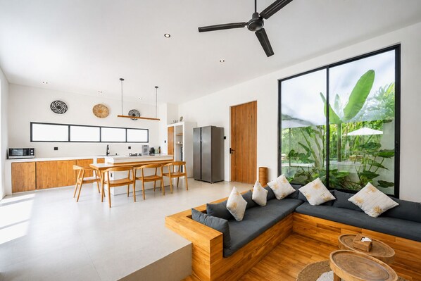 Una cocina moderna con comedor, un ventanal con vistas a zonas verdes y un rincón de descanso con cojines.