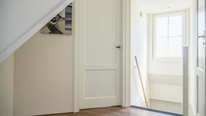 Una habitación con piso de madera, una puerta blanca y un ventanal.