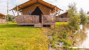Varias cabañas de madera con porches abiertos y un área verde frente a ellas.