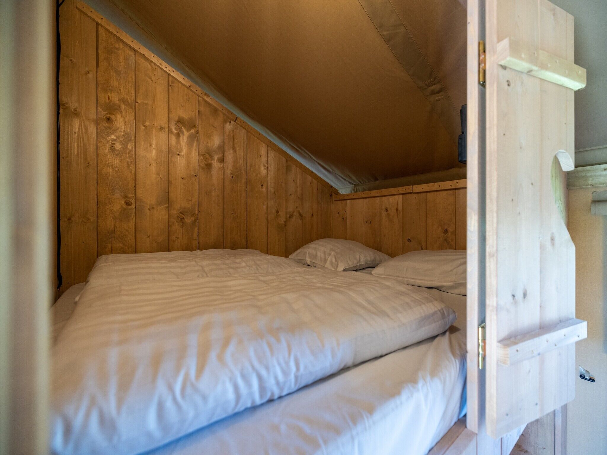 A wooden bunk bed with two pillows and a wooden headboard.
