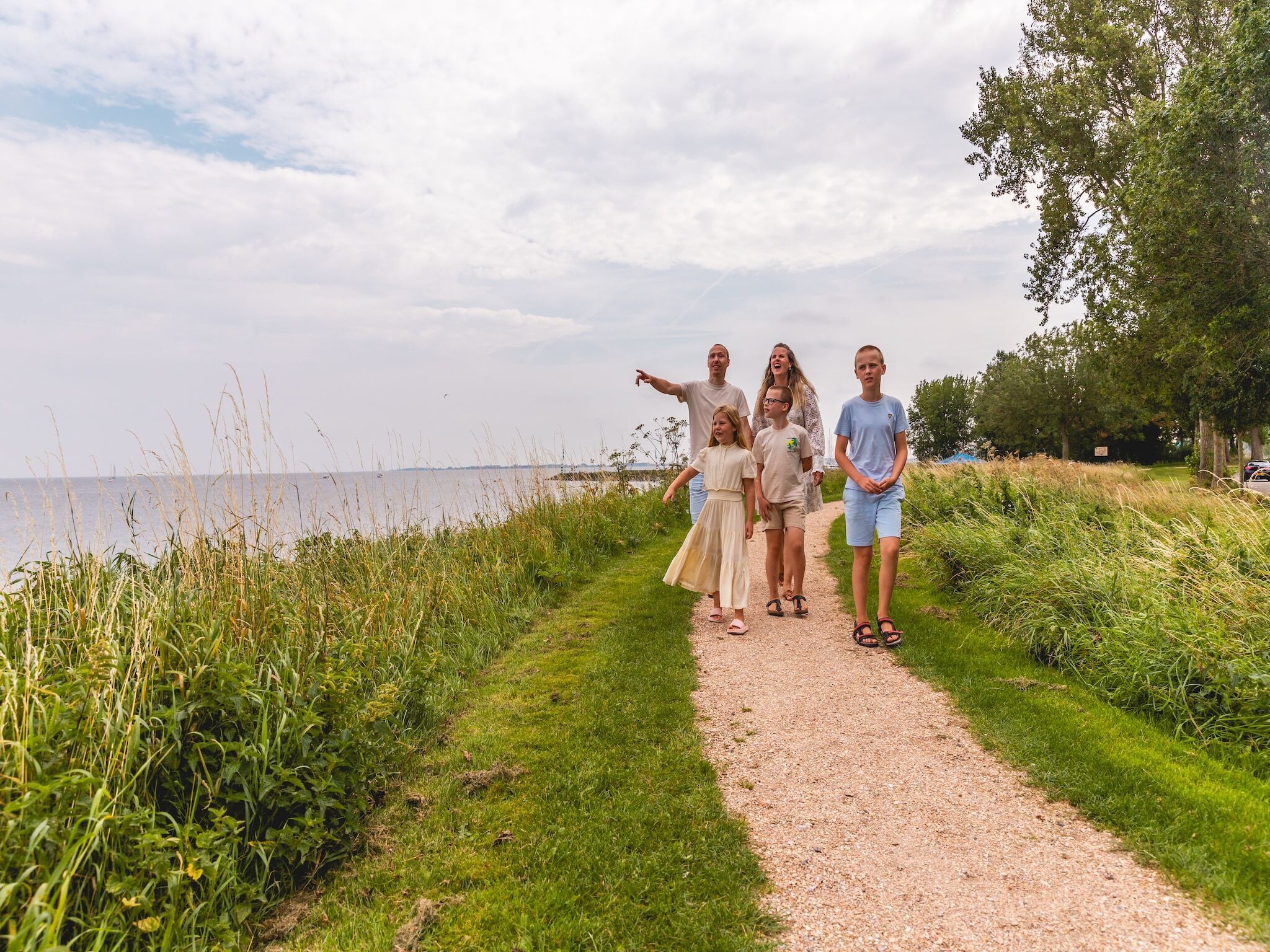 A gravel path leading to a body of water, surrounded by greenery.