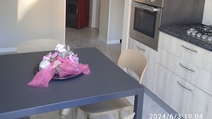 Una cuina moderna amb electrodomèstics d'acer inoxidable, una taula de dinar amb caires i un arranjament floral decoratiu.