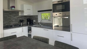 Eine moderne Küche mit weißen Schränken, einer schwarzen Arbeitsplatte, einem eingebauten Backofen und einer Pendelleuchte.