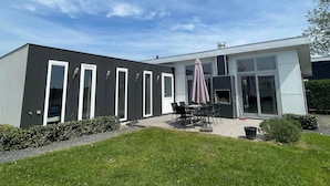 Ein modernes Gebäude mit einer Terrasse, die Sitzgelegenheiten und einen überdachten Tisch bietet.