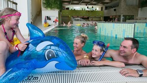 Een binnenzwembad met meerdere banen, een badmeesterstandplaats en een grote opblaasbare dolfijn.