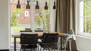 Een eetruimte met een tafel, stoelen en hanglampen.