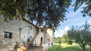 A stone building with a brick water feature, surrounded by greenery and a clear sky.