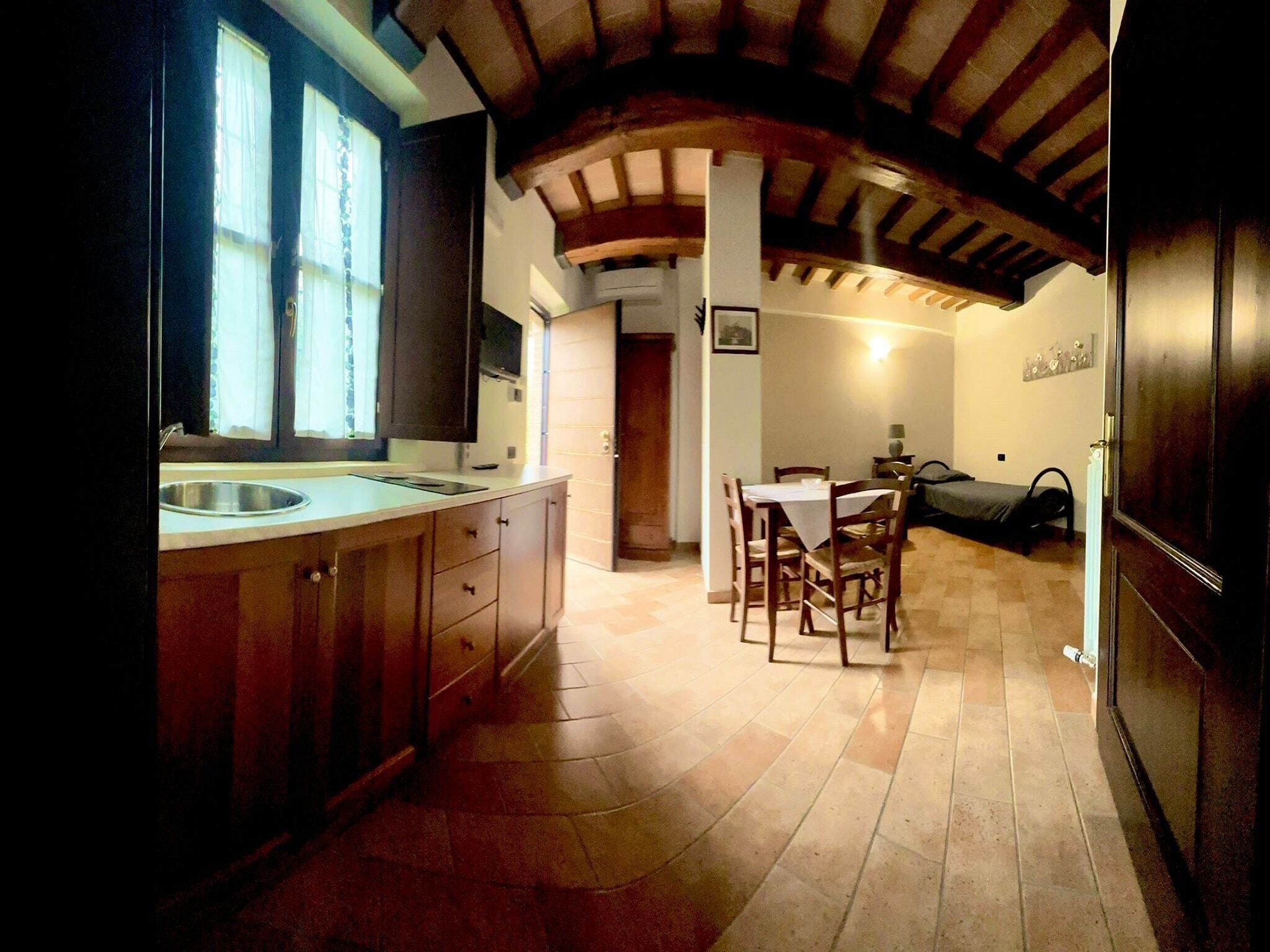 Une cuisine avec des meubles de rangement en bois, un évier et un coin repas comprenant une table et des chaises.