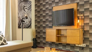 A modern living room with a sofa, a coffee table, and a TV mounted on a geometric-patterned wall.
