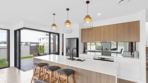 Une cuisine moderne dotée d’un grand îlot central, de tabourets de bar, de luminaires suspendus et offrant une vue sur l’extérieur.