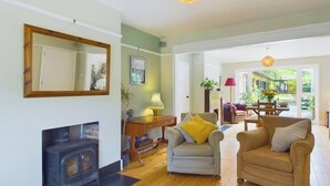 A living room with a fireplace, a sofa, a chair, and a dining area with a table and chairs.