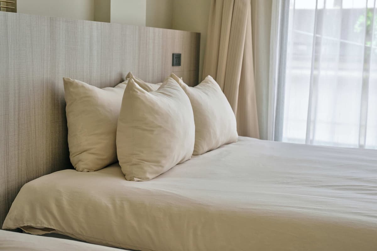 A neatly made bed with a headboard and a window with curtains.