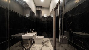 Un baño moderno con suelo de mármol, dos lavamanos, un inodoro y una zona de ducha.