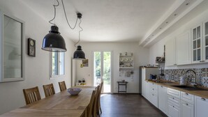 A spacious kitchen with a long wooden table, white cabinets, and a tiled backsplash. - Our Dream by Interhome (Alassio)