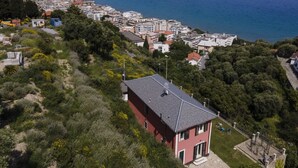 A coastal town with a prominent red building surrounded by greenery, overlooking a clear blue sea and a distant island. - Our Dream by Interhome (Alassio)