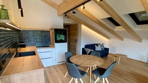 A modern kitchen with a wooden countertop, a sink, and a backsplash. There is a dining area with a round table and four chairs. - Deluxe One-Bedroom Apartment with Lake View (Sankt Wolfgang im Salzkammergut)