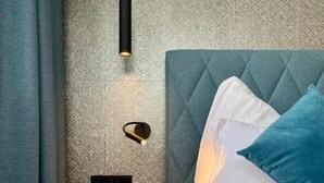 A bedroom with a bed, a nightstand, a wall-mounted light, and a textured wall. - Deluxe One-Bedroom Apartment with Lake View (Sankt Wolfgang im Salzkammergut)