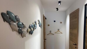 A hallway with a wooden floor, a white door, and a wall with decorative fish sculptures. - Deluxe One-Bedroom Apartment with Lake View (Sankt Wolfgang im Salzkammergut)