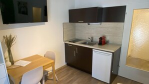 A compact kitchen with a sink, a small refrigerator, and a dining area with a table and chairs.