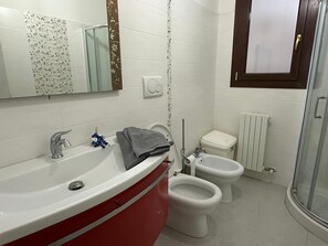 Een douche, een bidet, handdoeken, toiletpapier