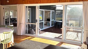 A room with a wooden ceiling, a dining area with a table and chairs, and a sliding glass door leading to an outdoor space with a patio and a view of the outdoors. - Yasmin Cottage - for an instant holiday feel.  (Kinloch)