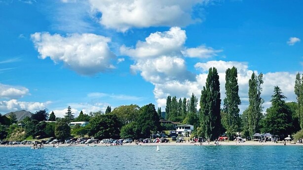 A beach with a clear blue sky, tall trees, and a calm sea. - Yasmin Cottage - for an instant holiday feel.  (Kinloch)