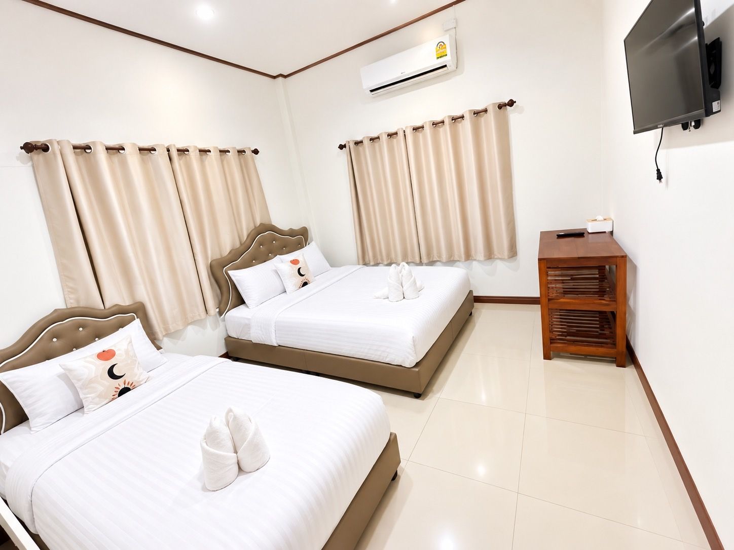 Quarto de hotel com duas camas, uma televisão e ar condicionado.