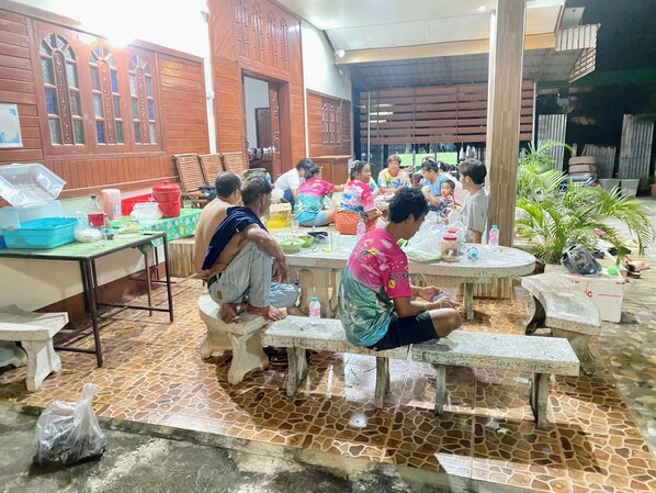 A communal dining area with stone-tiled flooring, wooden tables, and benches. - BaanKhunTong Chiang Khan (Chiang Khan)