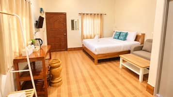 A hotel room with a bed, a sofa, a wooden table, a desk, a chair, a TV, and a door.
