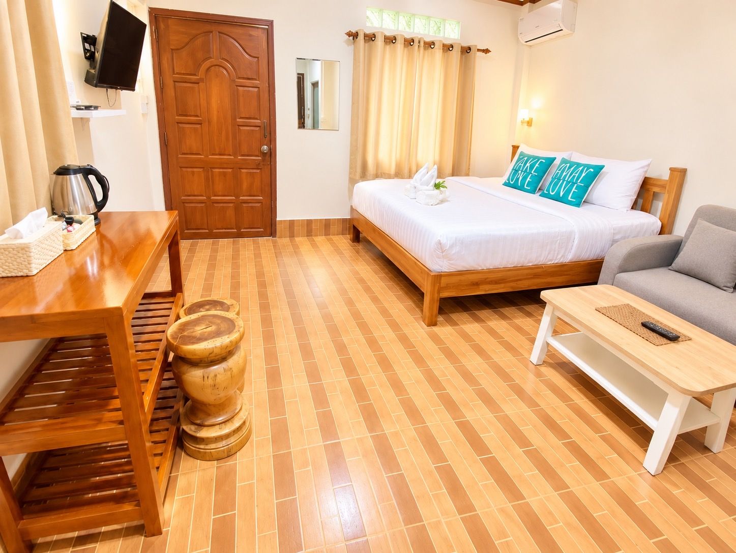 Habitación de hotel con una cama de madera, un sofá, una mesa de madera y un taburete pequeño de madera.