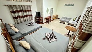 Habitación de hotel con dos camas, un sofá, un televisor y una mesita.