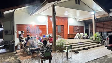 Un área de comedor al aire libre con un porche cubierto, una parrilla y un espacio de estar para invitados.