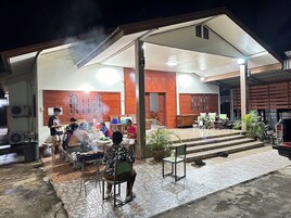Un área de comedor al aire libre con un porche cubierto, una parrilla y un espacio de estar para invitados.