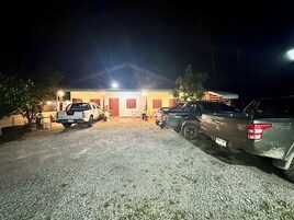 A building with a gravel driveway and parked vehicles.