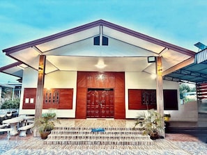 A modern building with a prominent entrance, a covered porch, and a tiled patio area. - BaanKhunTong Chiang Khan (Chiang Khan)