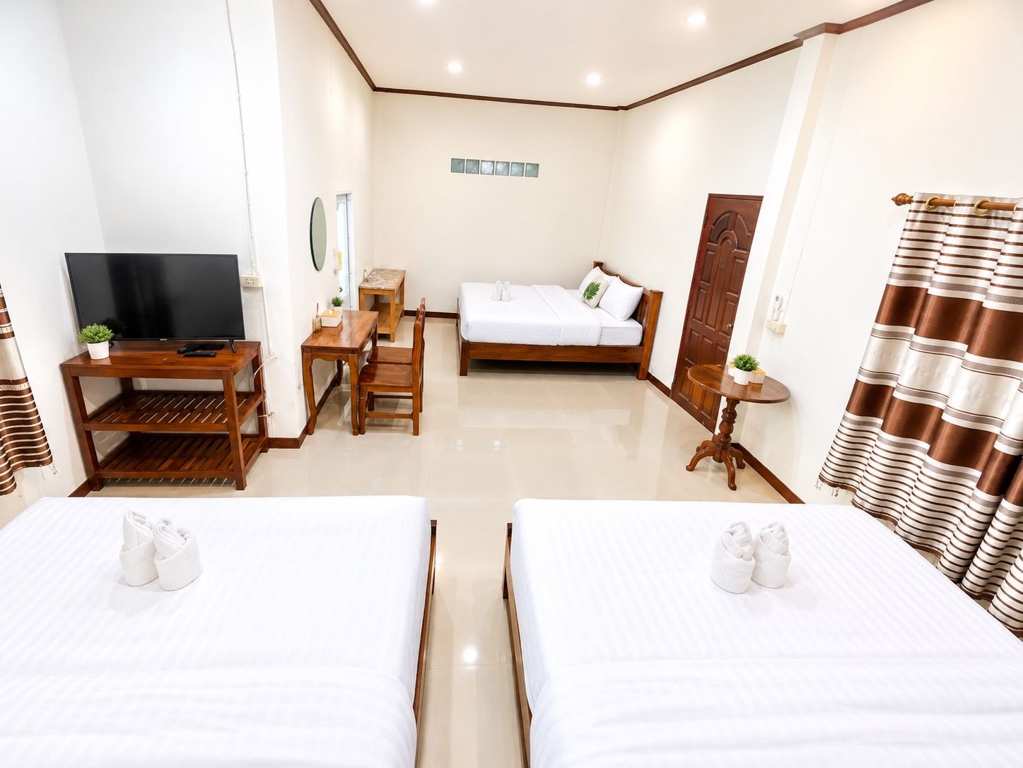 A hotel room with two beds, a TV, a desk, and a small table.