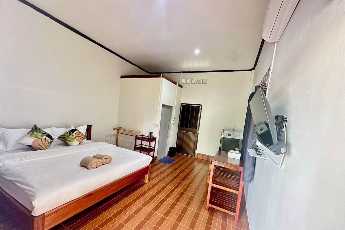 Quarto de hotel com cama, televisão, escrivaninha e porta do banheiro.