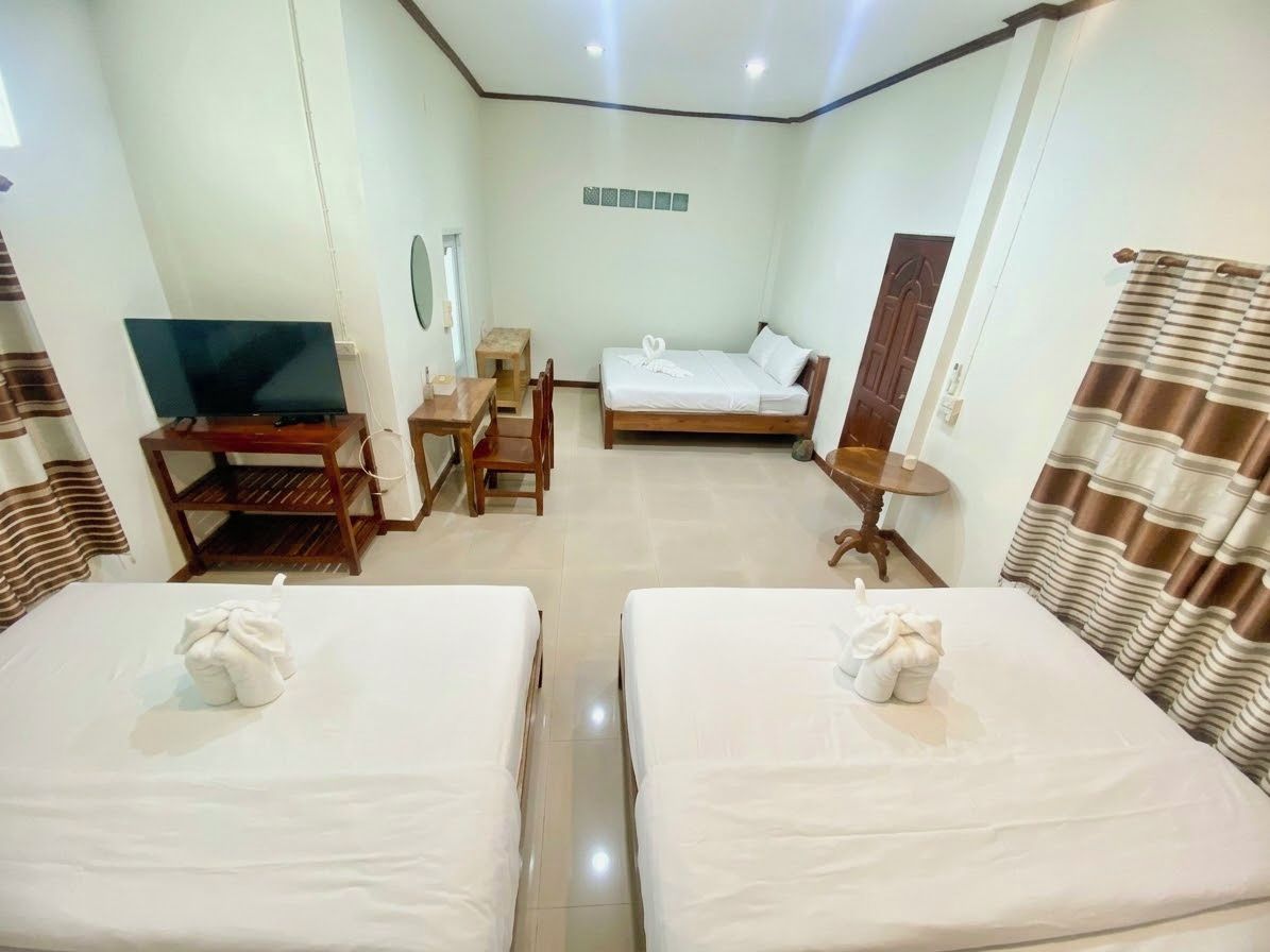 A hotel room with two beds, a television, a desk, and a small table.
