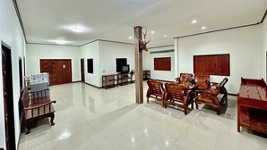 Amplia sala de estar con una gran mesa de madera para comer, varias sillas, un televisor y una cornamenta decorativa en la pared.