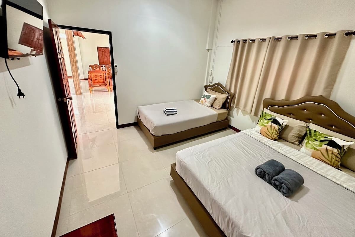 Quarto de hotel com cama, mesa de cabeceira, uma cadeira e vista para o corredor.